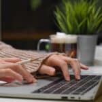 Hands typing on a laptop